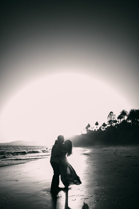 Couple laughing on the sand during a golden hour Butterfly Beach engagement session
