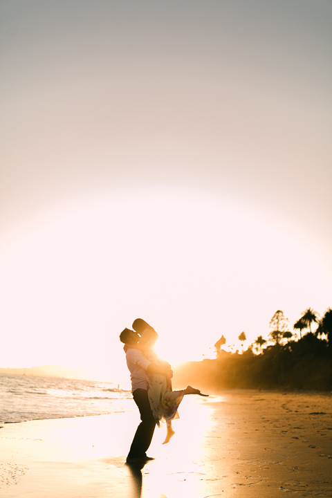 Couple laughing on the sand during a golden hour Butterfly Beach engagement session