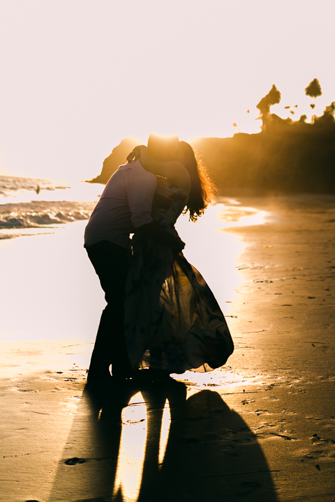Couple laughing on the sand during a golden hour Butterfly Beach engagement session