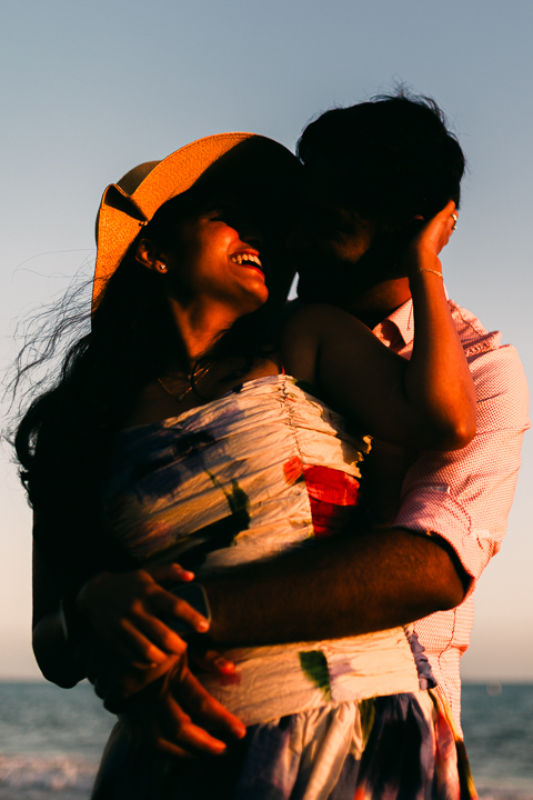 Couple laughing on the sand during a golden hour Butterfly Beach engagement session