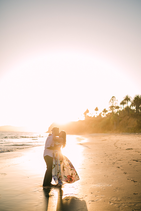 Couple laughing on the sand during a golden hour Butterfly Beach engagement session