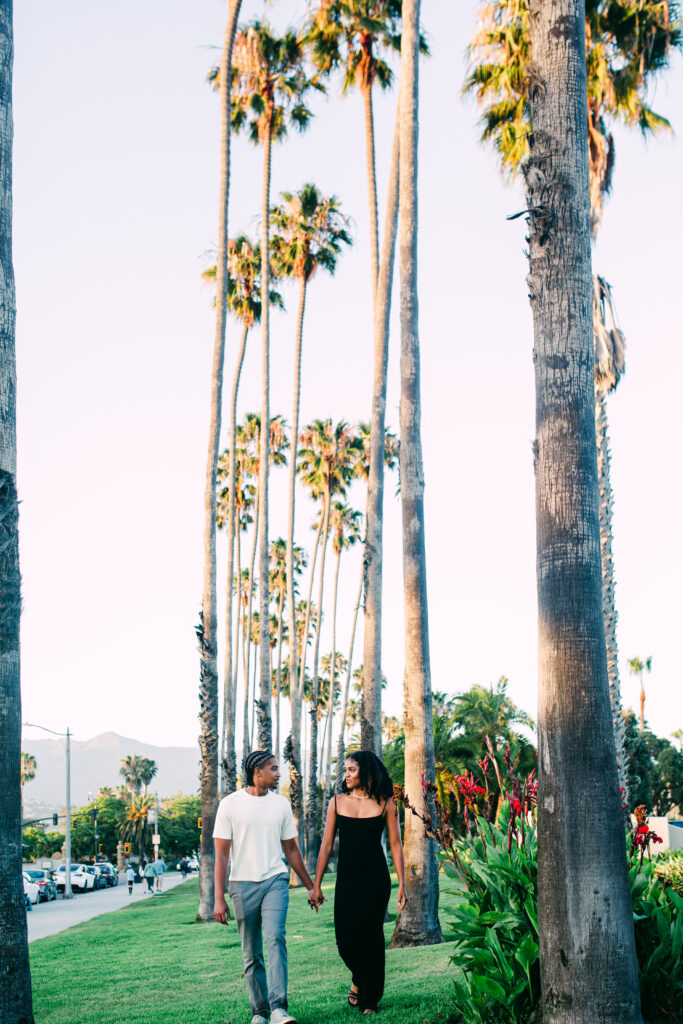 Palm strip, walking: Engaged couple walking hand in hand under palm trees along Cabrillo Boulevard in Santa Barbara